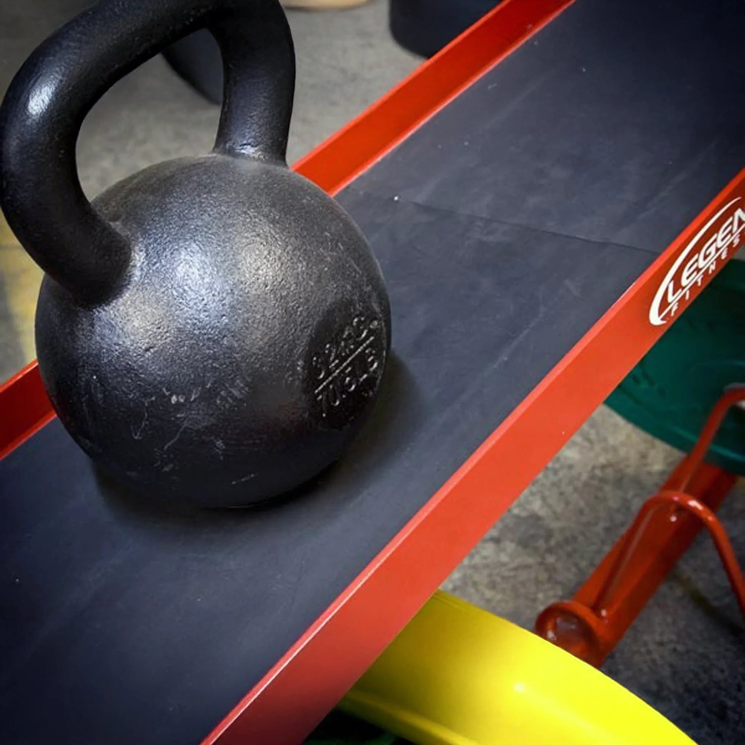 A black kettlebell on a red and black weightlifting storage rack