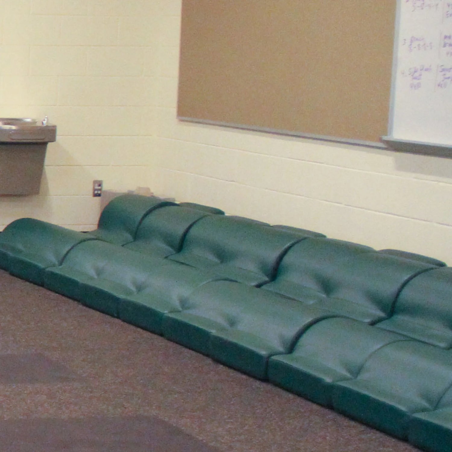 Two rows of green upholstered fitness pads in a gym setting