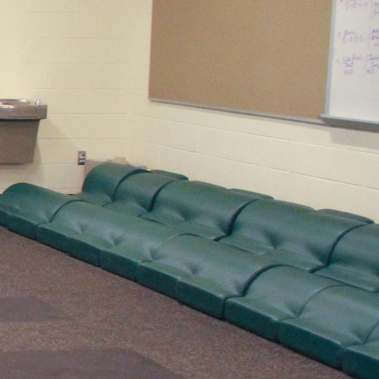 Two rows of green upholstered fitness pads in a gym setting