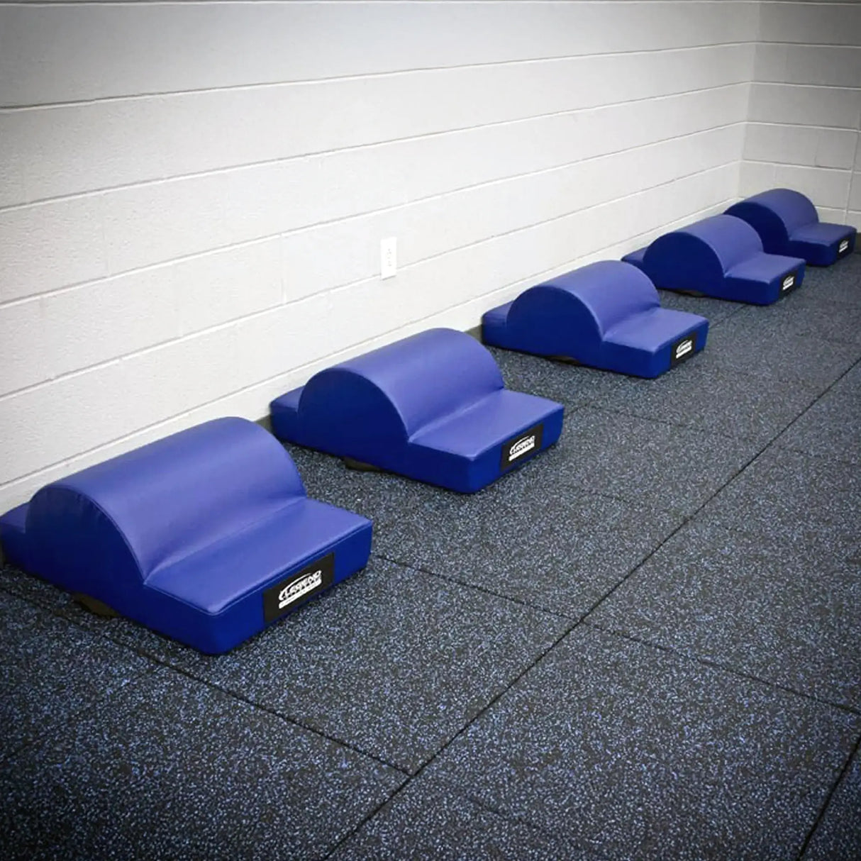 A row of blue upholstered fitness pads on a rubber tiled floor