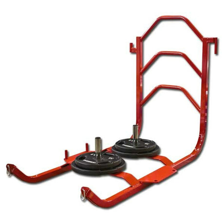 A red metal push sled with black weight plates on it on a white background
