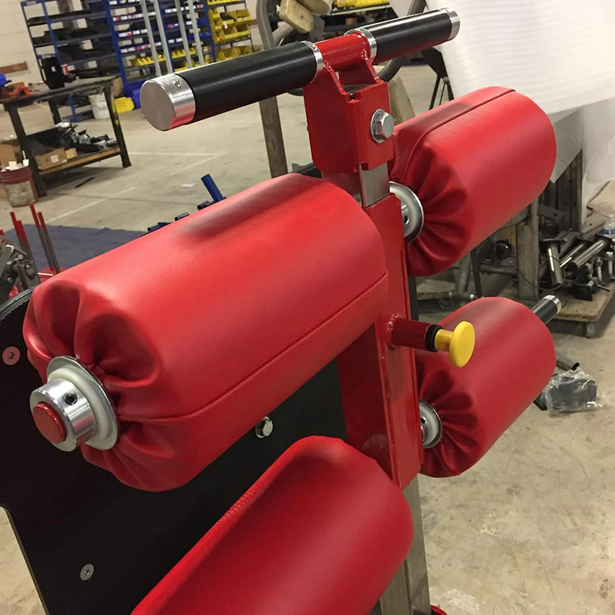 Four red foam roller pads on a red metal mount in a warehouse setting