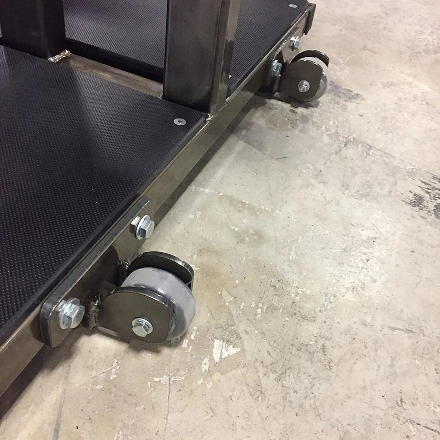 Close-up of a metal frame with wheels on a concrete floor