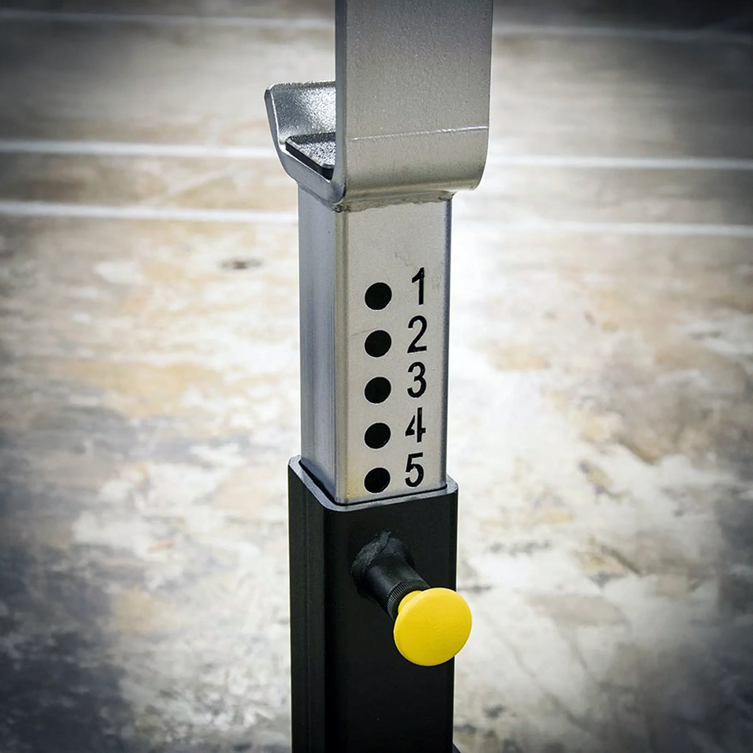 Silver and black barbell stand with numbers 1 through 5 and a yellow pop pin