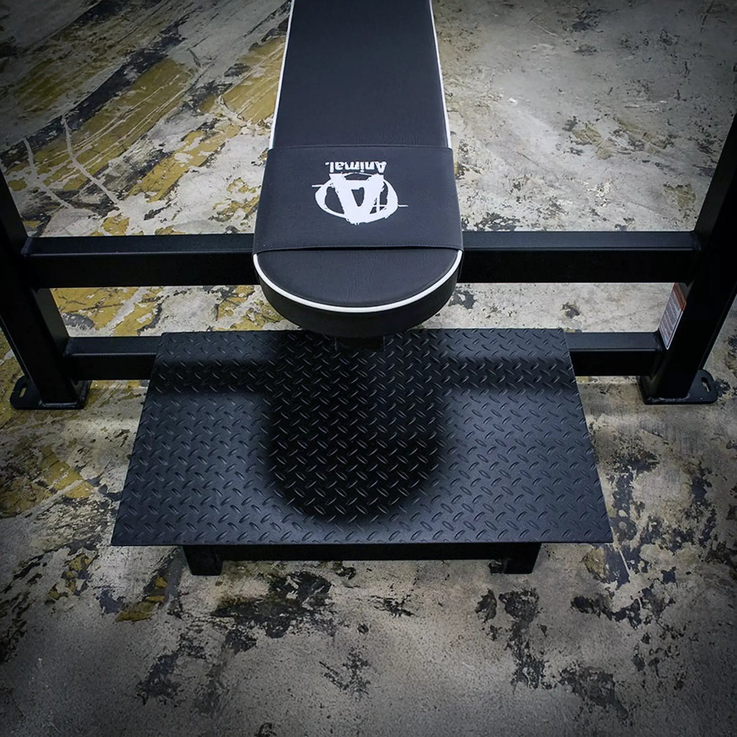 Black weight bench with a textured spotter platform on a concrete floor.
