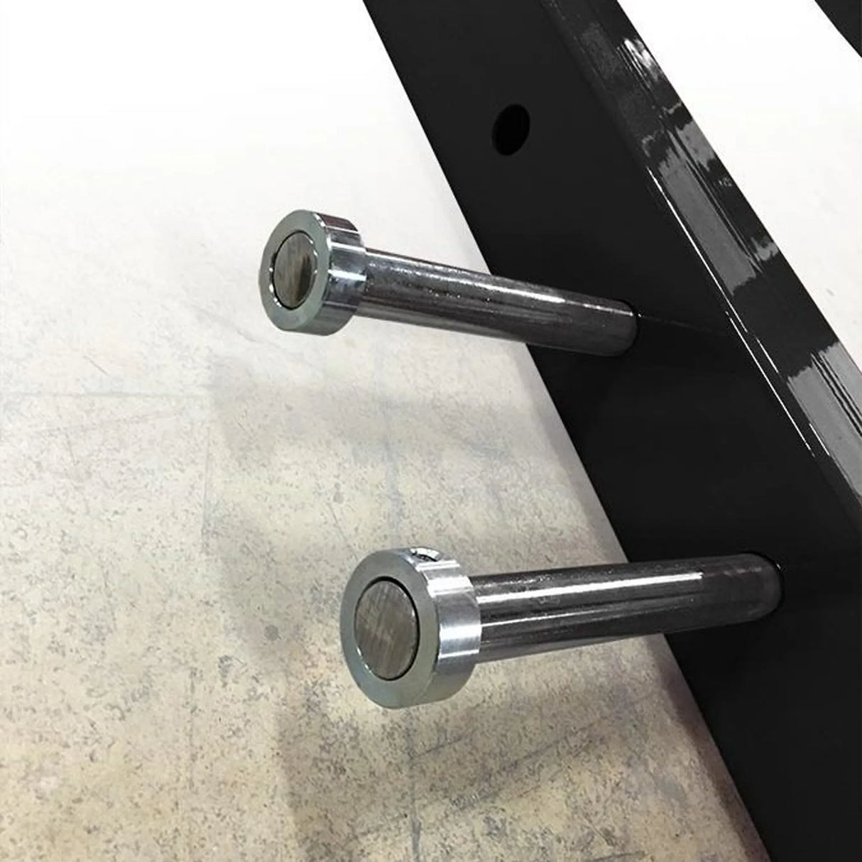 Two chrome pegs sticking out of a black metal beam