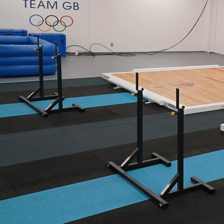 Two pairs of black squat stands in a gymnastics facility