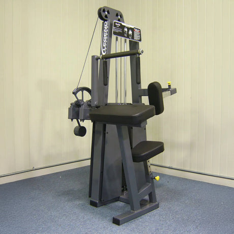 The Legend Fitness 910 Tricep Extension Machine by Legend Fitness features padded seats, a backrest, arm pads, and adjustable weights, designed for targeted tricep workouts in a carpeted room with a plain wall backdrop.