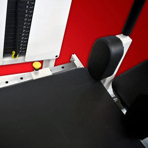 Close-up of the Legend Fitness 914 Supine Leg Press Machine by Legend Fitness, featuring a black padded seat, weight stack, adjustment pin, and arm rest set against a bright red wall background.