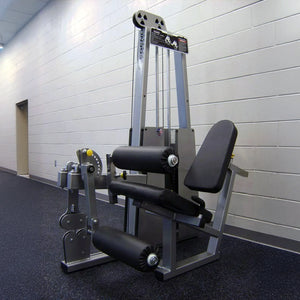 The Legend Fitness 918 Leg Extension / Leg Curl Combo Machine by Legend Fitness features padded seats, supportive rollers, and an adjustable weight stack, shown here in an empty gym with gray walls and black flooring.