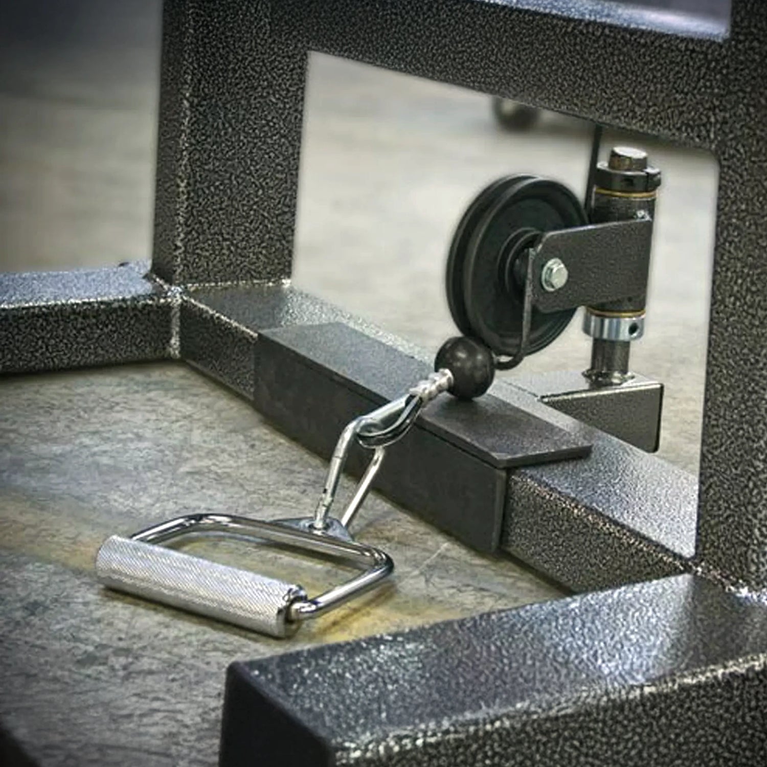 A close-up of the Legend Fitness 919 Cable Crossover Machine by Legend Fitness, highlighting the metal handle attachment linked to its pulley system on a textured metal frame.