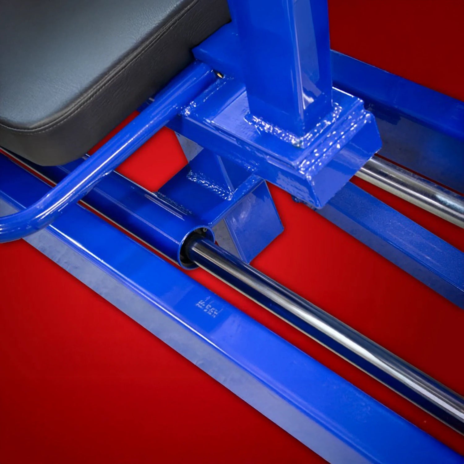 Close-up of the Legend Fitness 931 Seated Leg Press Machine by Legend Fitness, featuring blue metal, chrome rods, and a black cushioned seat set against a bright red background.