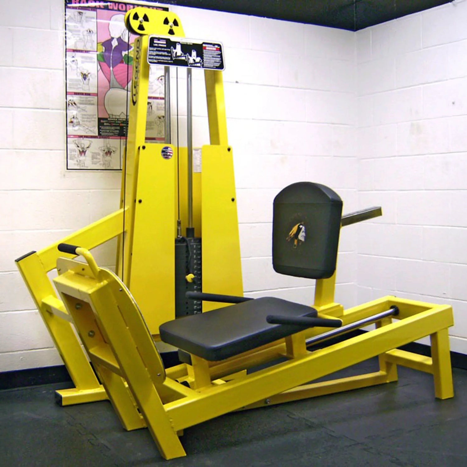 The Legend Fitness 931 Seated Leg Press Machine by Legend Fitness stands out in a gym corner with white brick walls, black flooring, and a workout poster displayed on the wall behind the equipment.