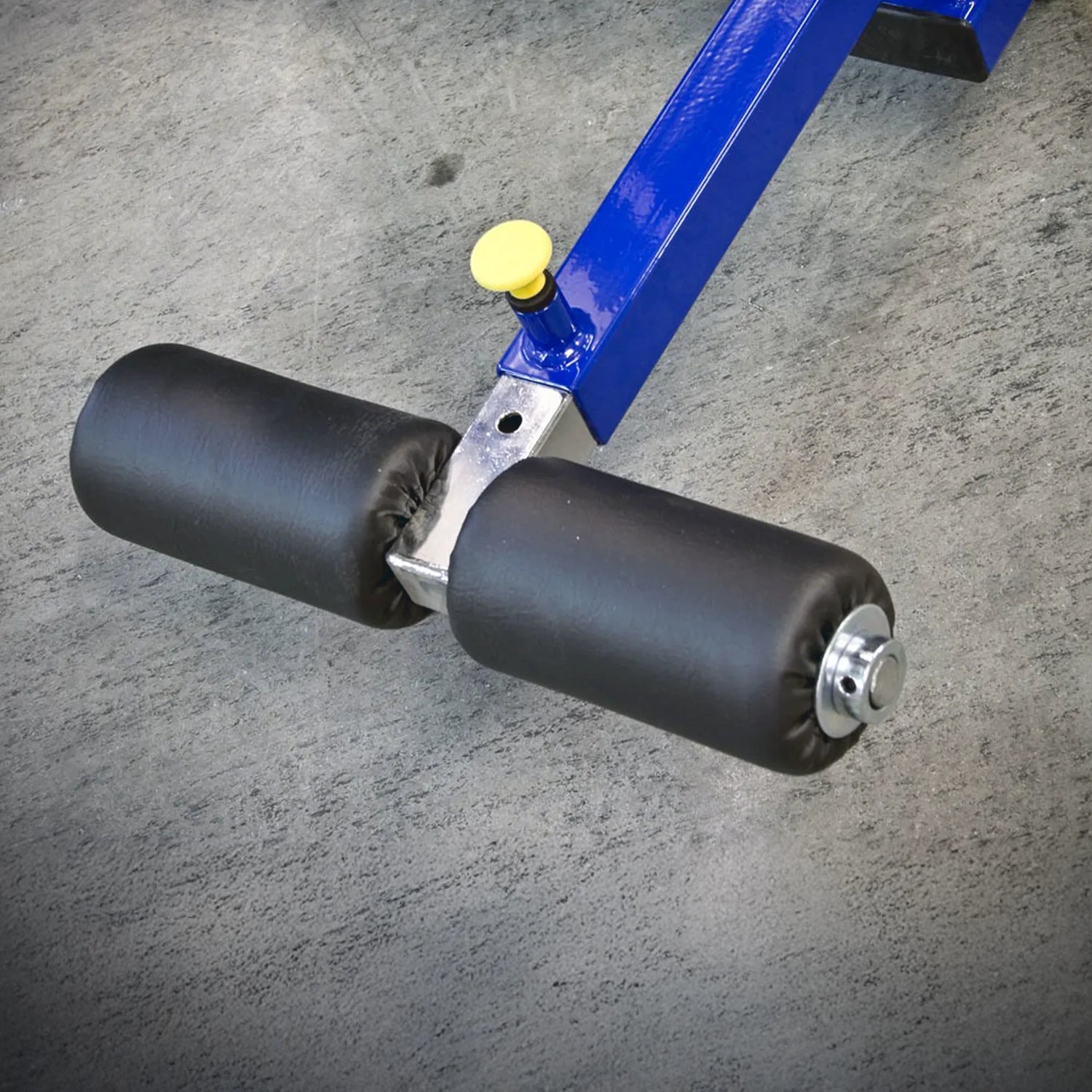 Close-up of the Legend Fitness 941 Ab Crunch Machine by Legend Fitness, featuring two black padded rollers and a yellow adjustment knob, on a textured gray floor.