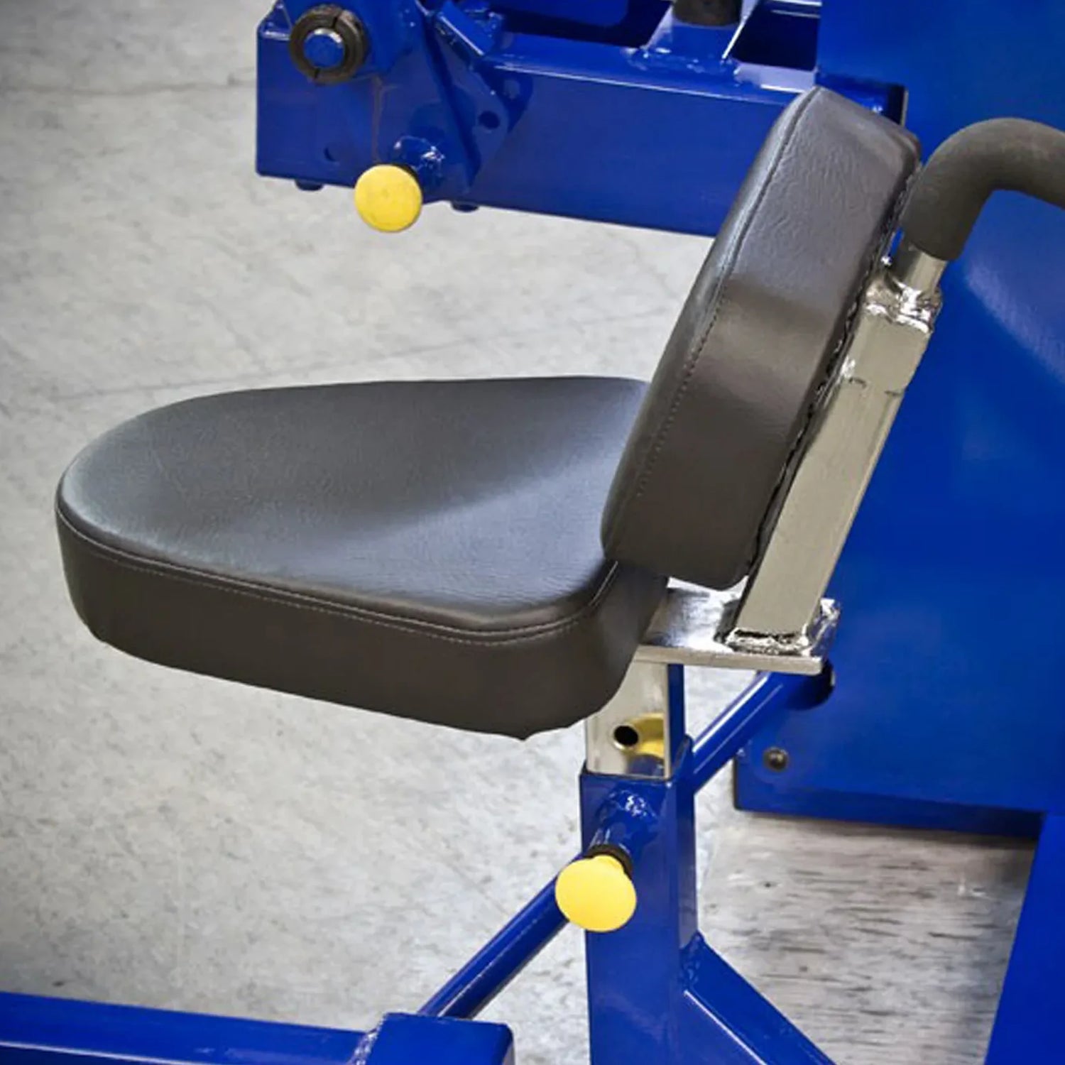 Close-up of the padded black seat and backrest of the Legend Fitness 941 Ab Crunch Machine by Legend Fitness, attached to a blue metal frame with yellow adjustment knobs, shown on a gray floor.