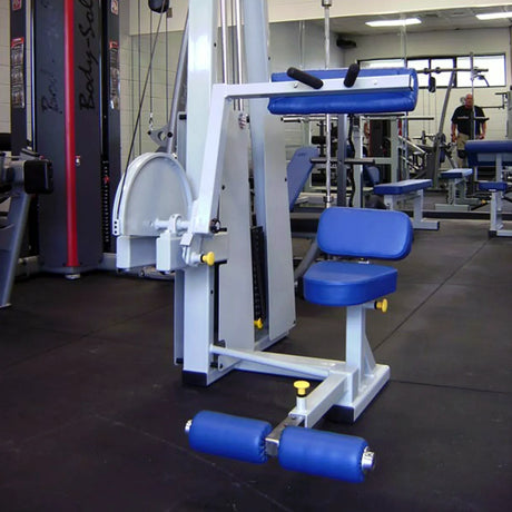 A Legend Fitness 941 Ab Crunch Machine by Legend Fitness, featuring a padded blue and white seat and metal frame, is positioned in an empty fitness center with other exercise equipment visible in the background.