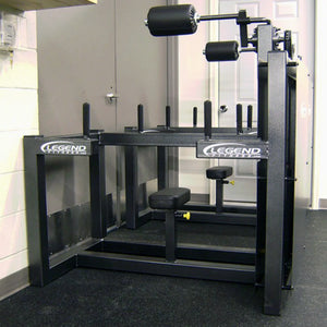 The Legend Fitness 943 Neck Machine is a black metal strength training gym machine with padded rollers and seat, shown in a room with white walls and rubber flooring. The Legend Fitness brand name is visible on the equipment.