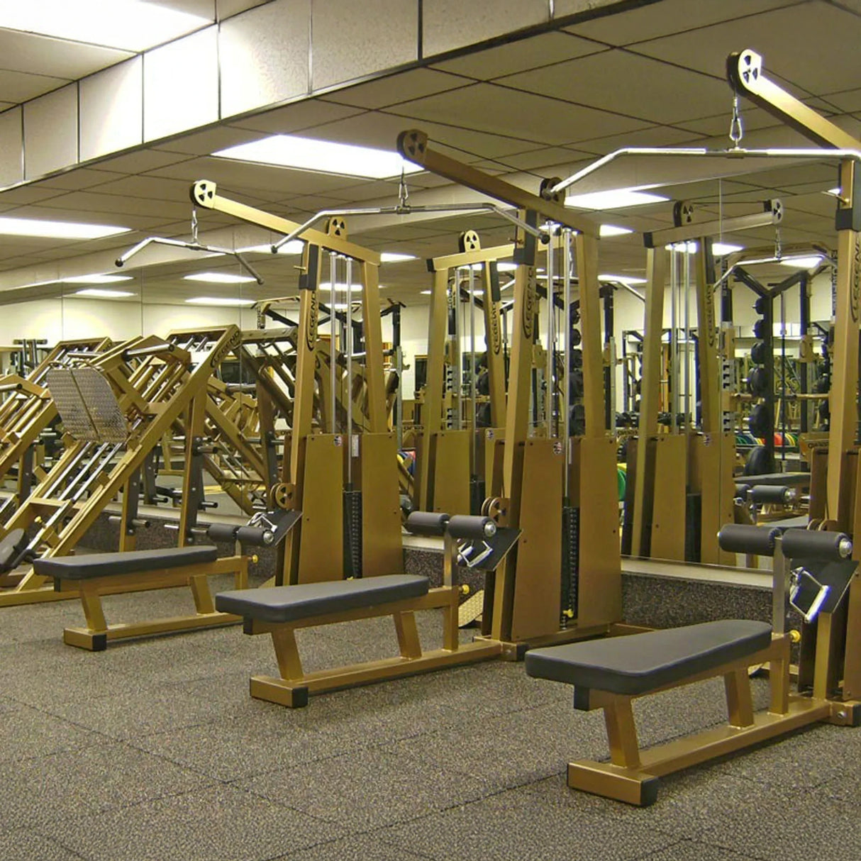 A gym featuring the Legend Fitness 945 Lat Pull / Low Row Combo Machine by Legend Fitness, with mirrored walls and a carpeted floor for a spacious and organized workout area.