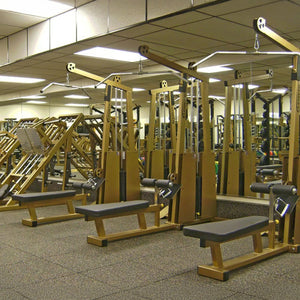 A gym featuring the Legend Fitness 945 Lat Pull / Low Row Combo Machine by Legend Fitness, with mirrored walls and a carpeted floor for a spacious and organized workout area.