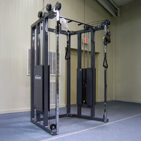 The Legend Fitness 953 Functional Trainer Machine by Legend Fitness is a black cable crossover with adjustable pulleys and weight stacks, featuring handles for strength exercises, set in a gym with blue carpet and beige walls.