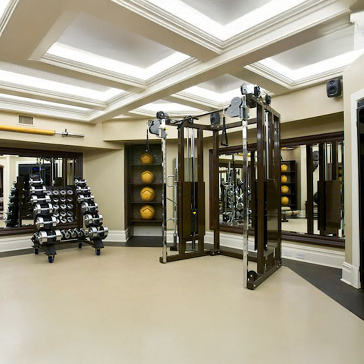 A modern gym features the Legend Fitness 953 Functional Trainer Machine, a rack of dumbbells, medicine balls on shelves, and large mirrors lining the walls beneath a coffered ceiling with bright lighting.