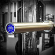 Silver barbell with a blue and silver label on a squat rack.
