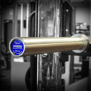 Silver barbell with a blue and silver label on a squat rack.