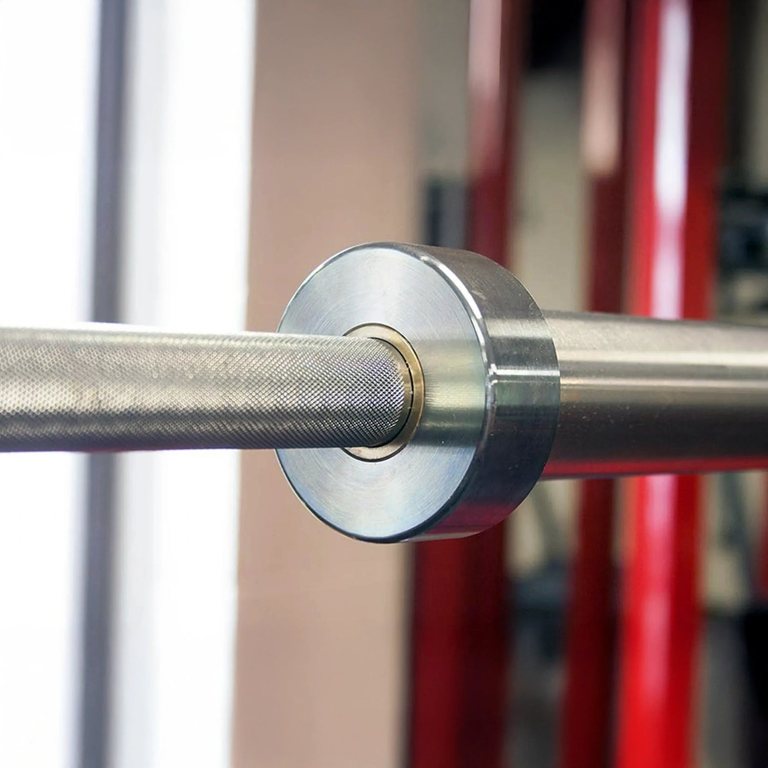 Close-up of a metallic barbell with a blurred gym background