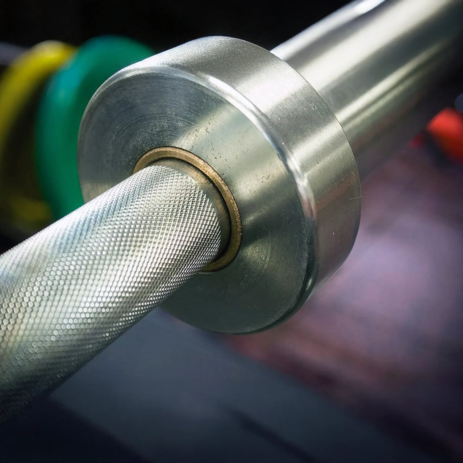 Close-up of a metallic barbell with weight plates in the background