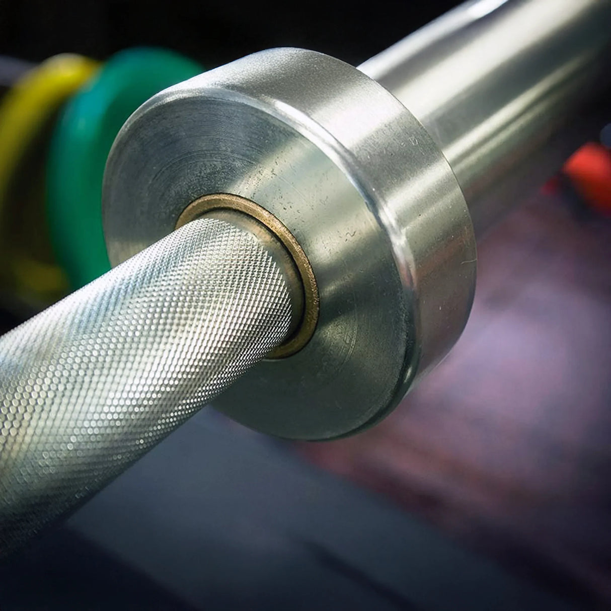 Close-up of a metallic barbell with weight plates in the background