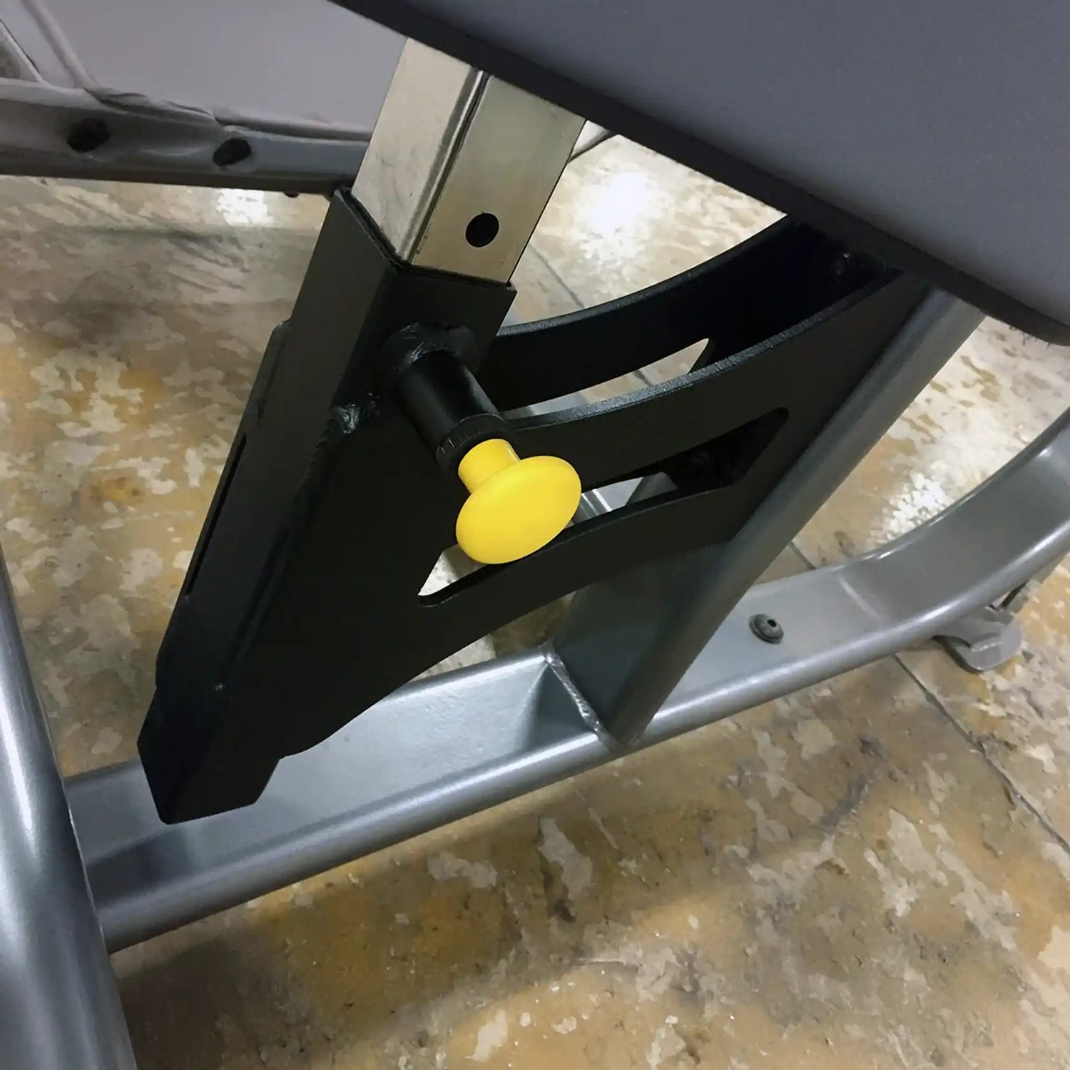Metal bracket with a yellow pop-pin on a concrete floor background