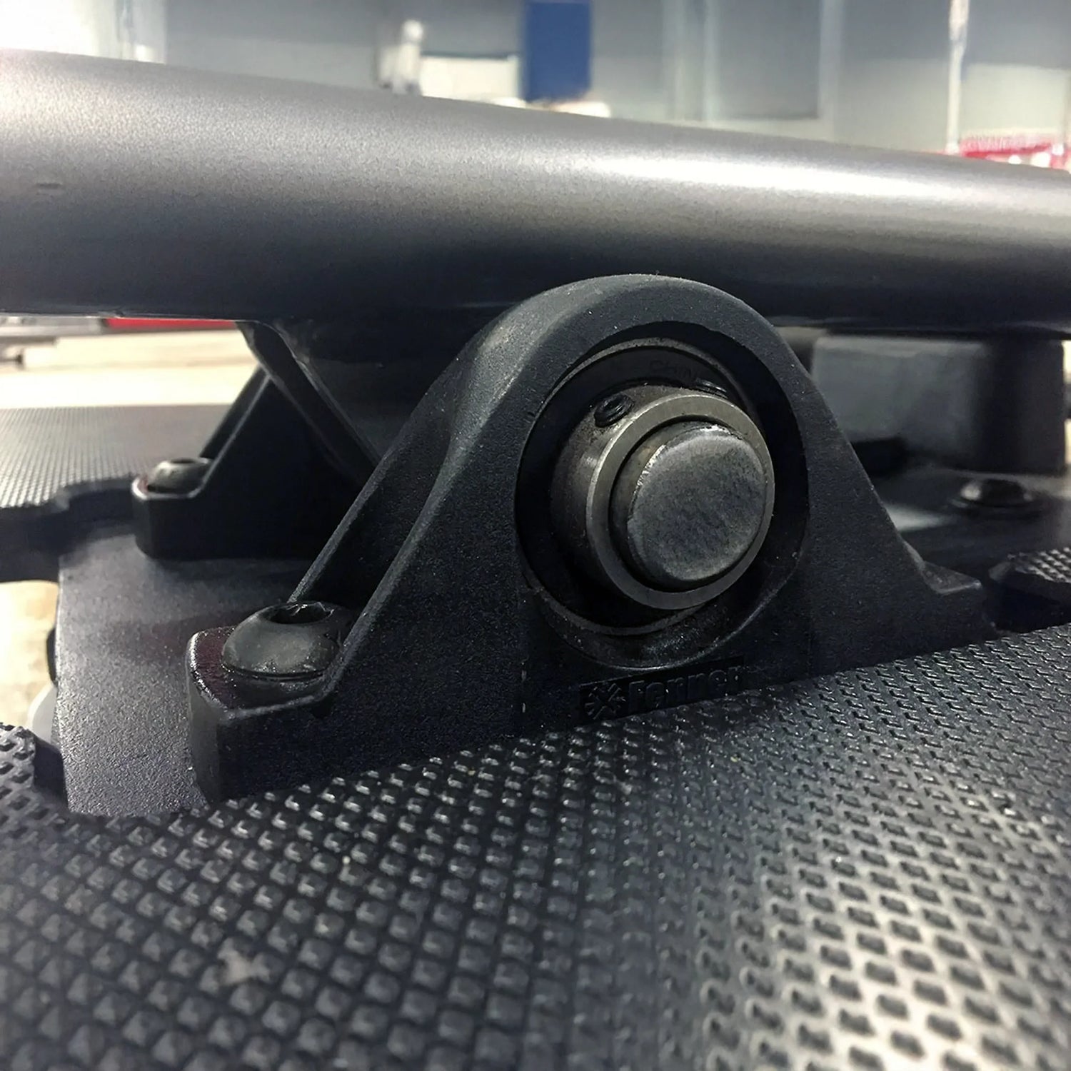 Close-up of a black metal component with a bolt on a textured surface.