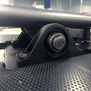 Close-up of a black metal component with a bolt on a textured surface.