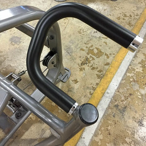Close-up of a gray framed piece of exercise equipment with a black handle on a concrete floor
