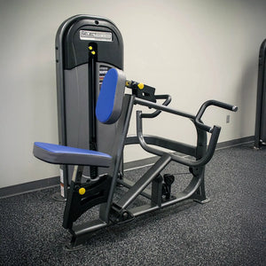 Gym machine with blue padding on a gray floor against a white wall
