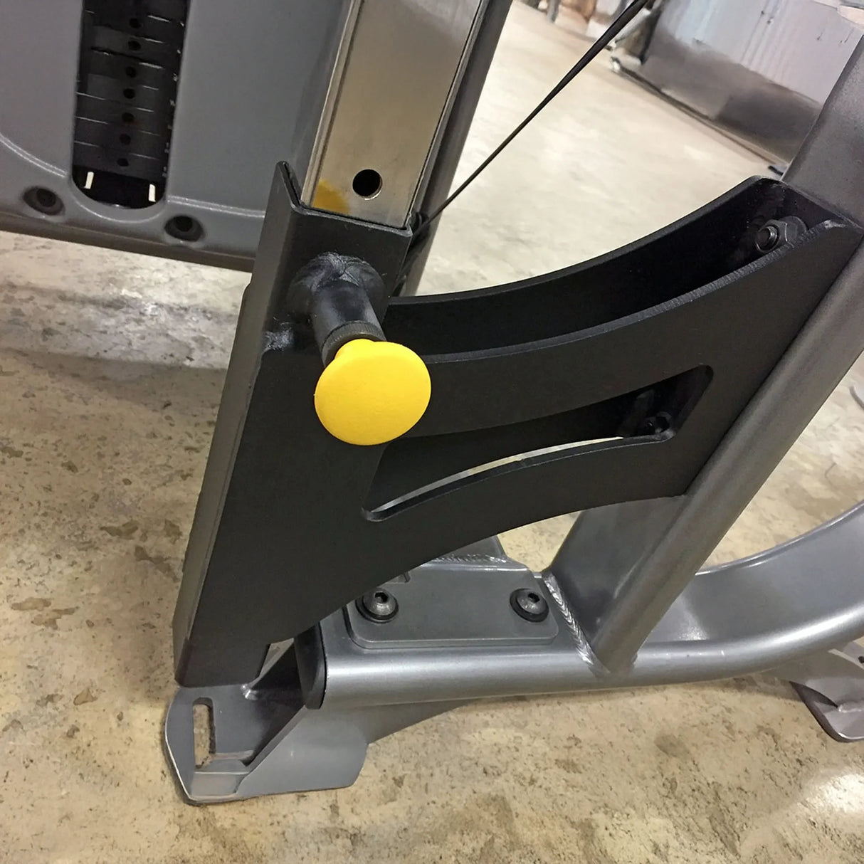 Close-up of a mechanical component with a yellow pop-pin on a concrete floor.