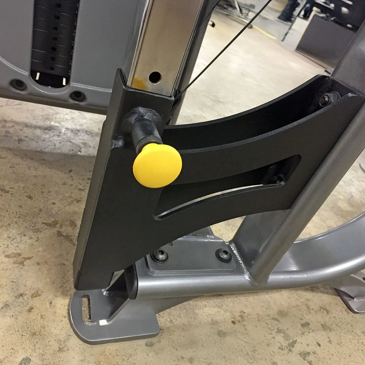 Close-up of a metal bracket with a yellow pop-pin on a concrete floor.