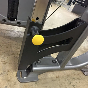 Close-up of a metal bracket with a yellow pop-pin on a concrete floor.