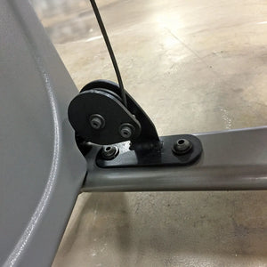 Close-up of a mechanical component on a gym machine with a black pulley and cable