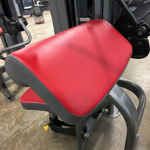 Red and gray seat on a piece of gym equipment with a blurred background