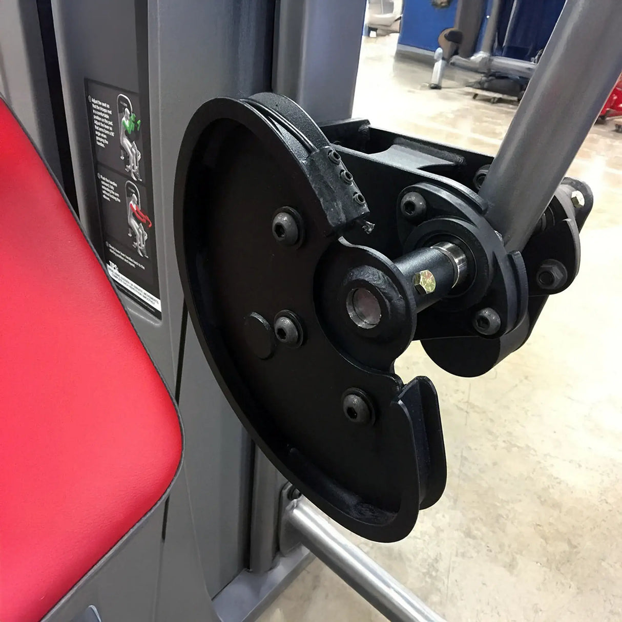 Close-up of a gym machine with red seat and metal components.