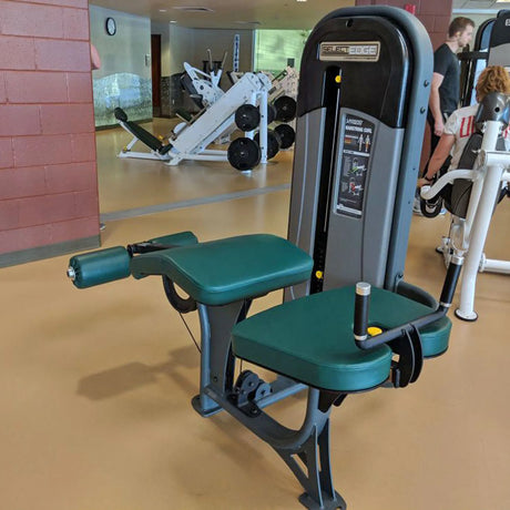 Gym machine with green seat and gray frame in a fitness center.