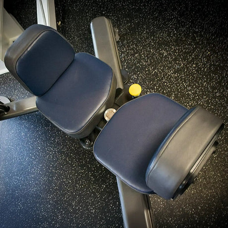 A close-up of the Legend Fitness SelectEDGE 1116 Torso Rotation Machine by Legend Fitness, featuring dark blue padded seats and armrests, set against a speckled black gym floor.