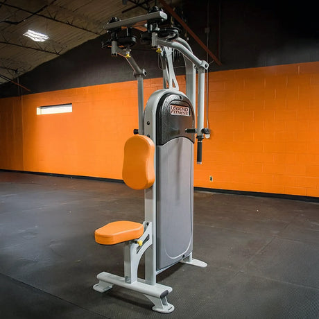 Gym machine with orange seat and gray frame against an orange wall.