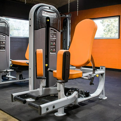 Gym machine with orange seat and gray frame in a fitness center.