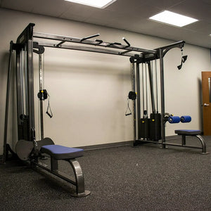 Gym equipment including a pull-up bar and weight bench in a room with beige walls and a door.