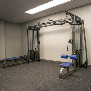 Gym equipment including a pull-up bar and weight bench in a room with gray carpet and beige walls.