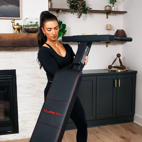A PowerBlock bench with a dip attachment a woman is attaching to the back