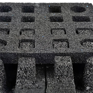 Close-up of the ECORE Quad Blok Connector for 2.5" Tiles by ECORE Athletic, featuring a textured black foam block with a grid of square and round holes on top; designed for secure tile installation and impact cushioning.