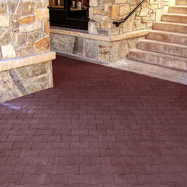 Red rubber paver patio leading up to a stone house and staircase